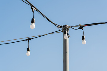 Hanging light bulbs on clear blue sky