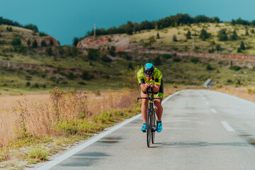 Naklejka premium Full length portrait of an active triathlete in sportswear and with a protective helmet riding a bicycle. Selective focus 