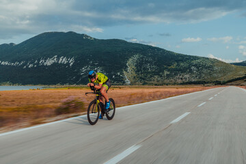 Obraz premium Full length portrait of an active triathlete in sportswear and with a protective helmet riding a bicycle. Selective focus 