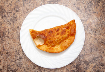 Cheburek from dough and minced meat in a white plate.