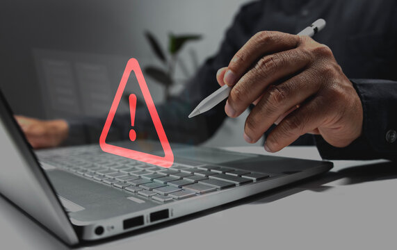 Businessman using laptop computer with triangle warning sign for error alert and hacker data protection