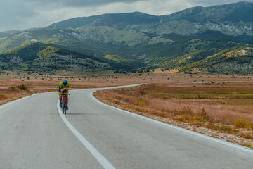 Fototapeta premium Full length portrait of an active triathlete in sportswear and with a protective helmet riding a bicycle. Selective focus 