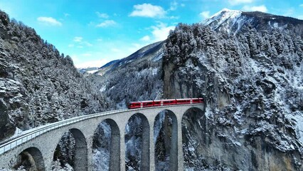 Aerial view of Train passing through famous mountain in Filisur, Switzerland. Landwasser Viaduct world heritage with train express in Swiss Alps snow winter scenery.  - Powered by Adobe