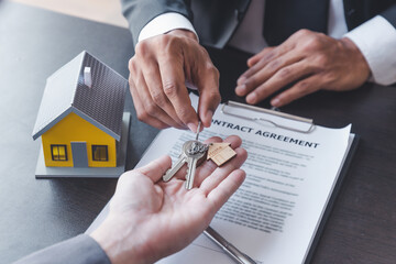 Home sales,home rental and real estate concept.Hands of estate agent giving keys to the Customer after sign the document while explain about the terms of the home purchase or rental agreement