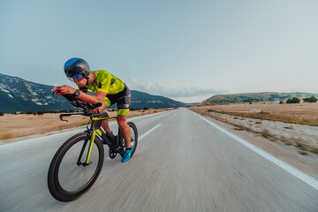 Full length portrait of an active triathlete in sportswear and with a protective helmet riding a...