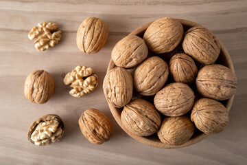 Peeled walnuts and whole walnuts in wooden bowl
