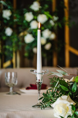 Festive table decorated with a composition of flowers and greenery, and candles in the banquet hall. Table newlyweds in the banquet area at the party in a restaurant. Wedding setup. Closeup.