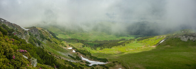Stormy clouds and low altitude mist are covering the mountain peaks and alpine grasslands of CLatorita Mountains - Carpathia. Springtime weather.