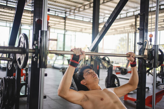 Asian man exercising with a barbell in the fitness