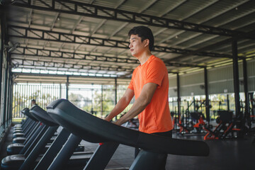 Asian men are happy jogging and running on a treadmill at gym. A man is jogging and doing cardio training. Healthy lifestyle concept. Doing exercise for longer life