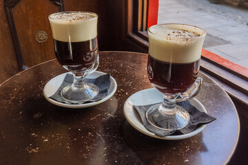 Two big glasses of dark Irish Coffee with foam. Drinks with alcohol in Irish Pub in Madrid, Spain