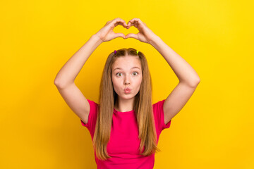 Obraz na płótnie Canvas Photo of teen age girl wearing t-shirt pouted lips kisses showing love heart symbol wait her boyfriend feelings isolated on yellow color background
