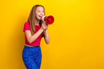 Photo of adorable good mood schoolgirl pink t-shirt showing v-sign hold loudspeaker look empty space isolated on yellow color background