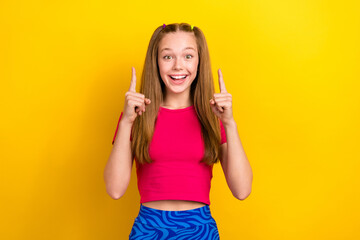 Photo of nice impressed schoolgirl with straight hairstyle wear pink t-shirt indicating empty space isolated on yellow color background