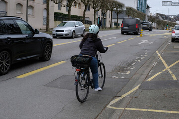Cycliste avec un casque roulant sur un boulevard de la ville de Vannes en Bretagne - obrazy, fototapety, plakaty