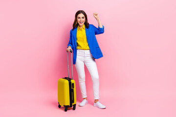 Photo of delighted positive person raise fist luck shout yes hold suitcase isolated on pink color background