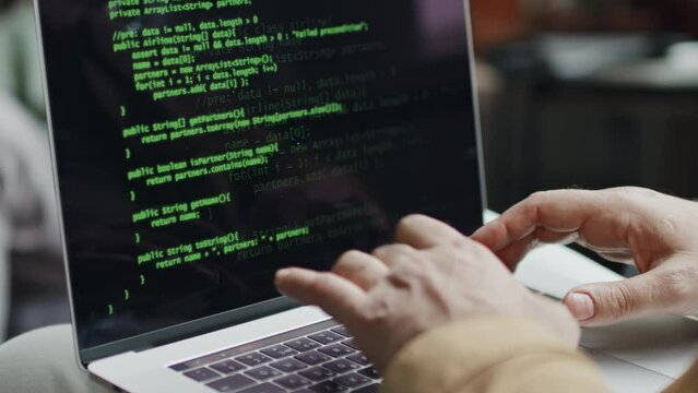 Close-up of It specialist writing codes on laptop computer, he developing new software
