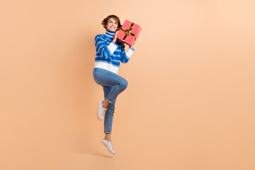 Fototapeta na wymiar Full length photo of funny pretty woman dressed striped sweater jumping rising present empty space isolated beige color background