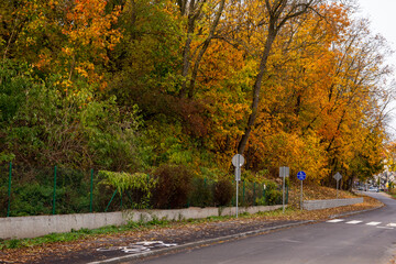 Obraz premium A retaining wall made of concrete elements protects the roadway and pavement from sliding down the slope. Autumn.
