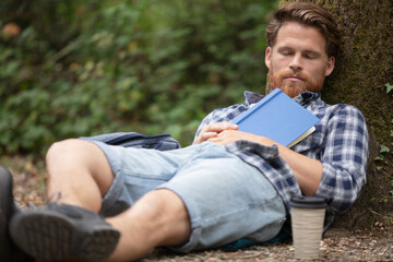 Fototapeta premium sleepy man under the tree with the book