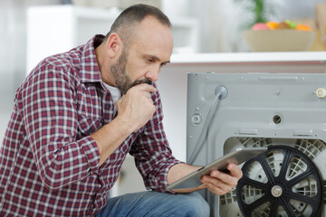 man using tablet to fix a washing machine