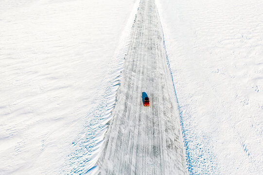 Cold Winter Sun Over An Isolated Car Traveling On Ice Road On Frozen Sea, Aerial View, Lulea, Norrbotten County, Lapland, Sweden, Scandinavia, Europe