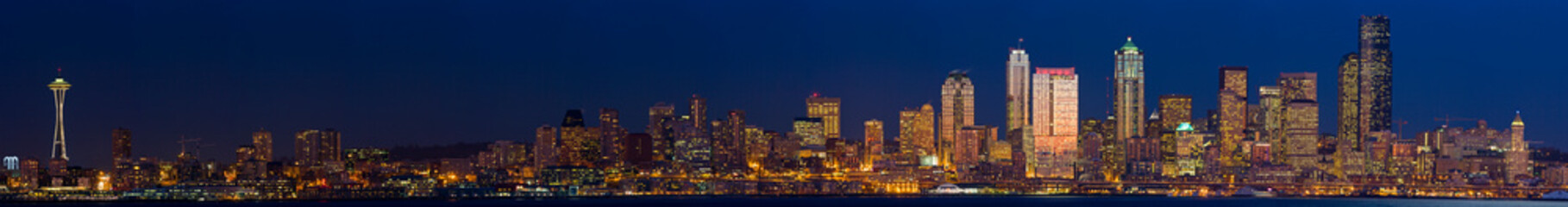 Fototapeta premium Panoramic skyline of Seattle with buildings reflecting the setting sun.