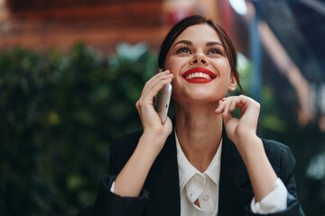 Woman blogger tourist sits in a cafe at a table with a phone in her hands conversation, mobile communication and internet in spring travel, video business call, freelance work online, smile with teeth