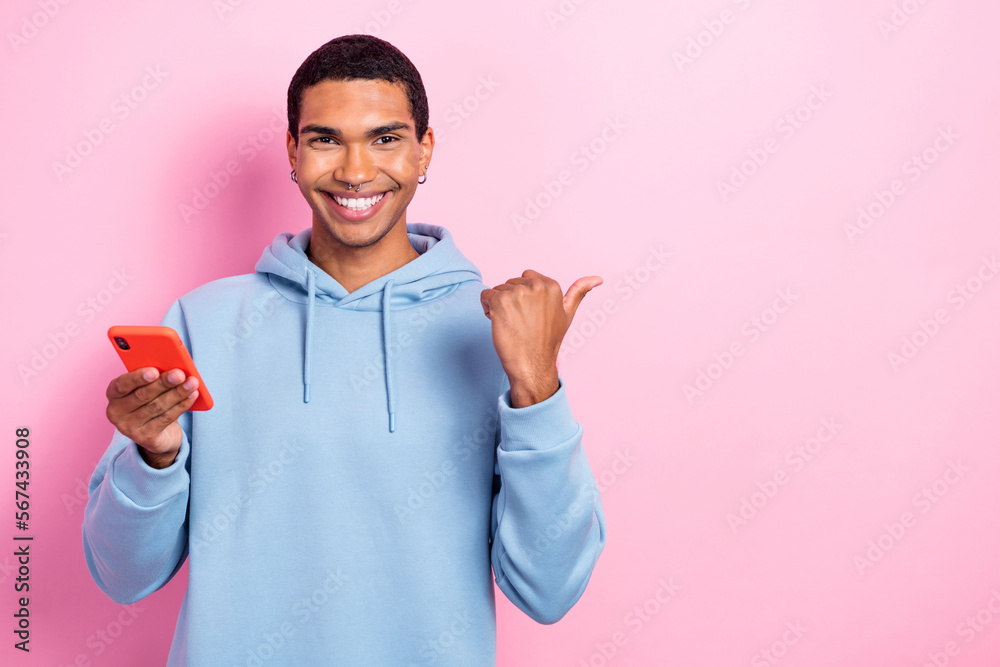 Sticker photo of cool positive guy hold telephone indicate finger empty space isolated on pink color backgro