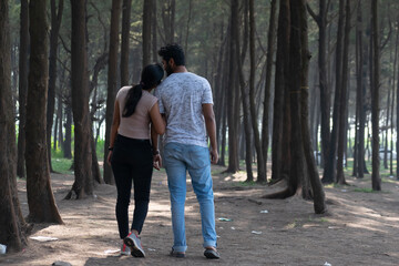 Beautiful young attractive tourist couple looking each other embracing, loving smiling cuddling walking in woods. 