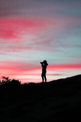 Femme qui prend une photo au coucher du soleil