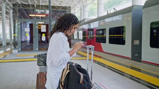 Young woman using phone while waiting train boarding at the station