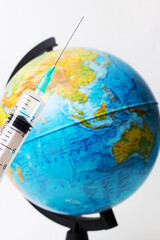 Syringe in hand on background of globe