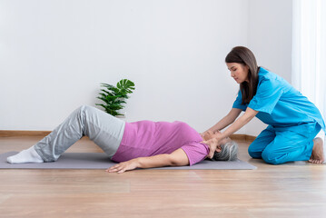 Asian physical therapist, doing shoulder muscles physiotherapy for an Asian elderly woman, to treat osteoarthritis and nerve pain in the shoulder, to nursing home and health care concept.