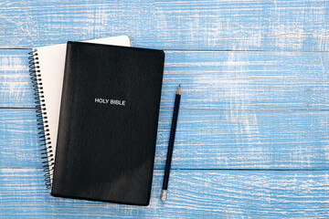 Holy bible book and notebook on blue wooden background, top view, copy space.