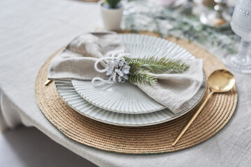 Christmas serving, plate, with a napkin on a branch of space on a table with a light tablecloth. Winter holiday theme, design with copy space. High quality photo