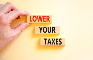 Lower your taxes symbol. Concept words Lower your taxes on wooden blocks on a beautiful white table white background. Businessman hand. Business tax lower your taxes concept. Copy space.