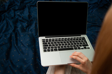 Woman using laptop computer at home, blank black screen mockup