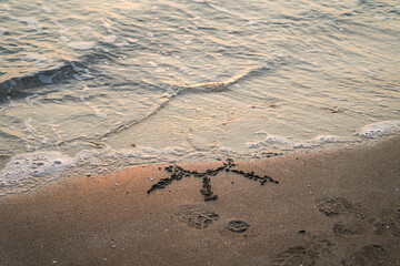 Sun emoji on beach sand, half of it closed with wave