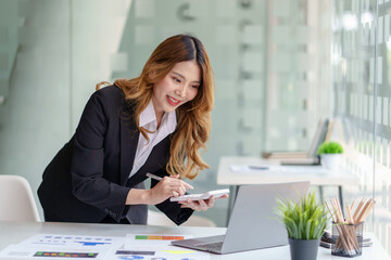 Asian businesswoman working with laptop computer using calculator to calculate business finance and accounting statistics at office.