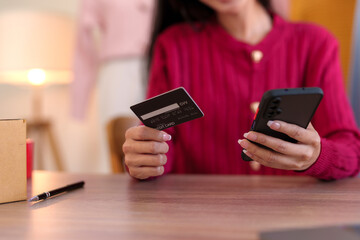 Young business woman is using smartphone for online shopping and using credit card for payment through banking application for online shopping.