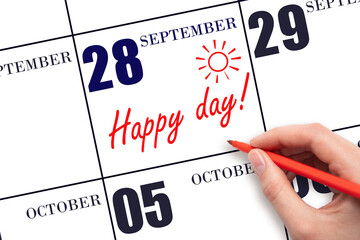 Hand writing the text HAPPY DAY and drawing the sun on the calendar date September 28