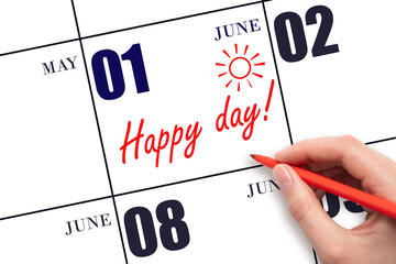 Hand writing the text HAPPY DAY and drawing the sun on the calendar date June 1
