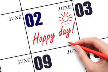 Hand writing the text HAPPY DAY and drawing the sun on the calendar date June 2
