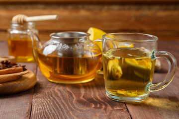 A transparent mug of lemongrass tea on a table next to anise, cinnamon, ginger and honey on a wooden board.