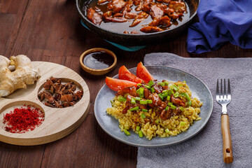 Fried chicken pieces in soy and pad thai sauce in a pan on the table with other food and spices.