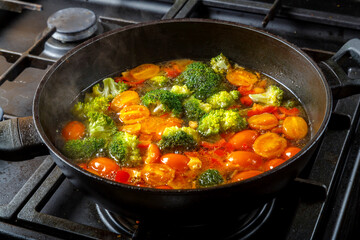 Stewed vegetables beans broccoli tomatoes stewed with spices in a frying pan.