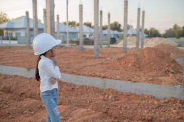 Obraz na płótnie Canvas Engineer kid concept,Asian little girl wear engineer uniform working at site of building