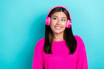 Portrait of cute lovely lady stylish pink clothes interested look empty space cool offer low price earbud isolated on cyan color background