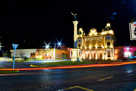 view of street at night with building  illuminated, and lights of car in foreground, hidalgo theather in parral chihuahua 